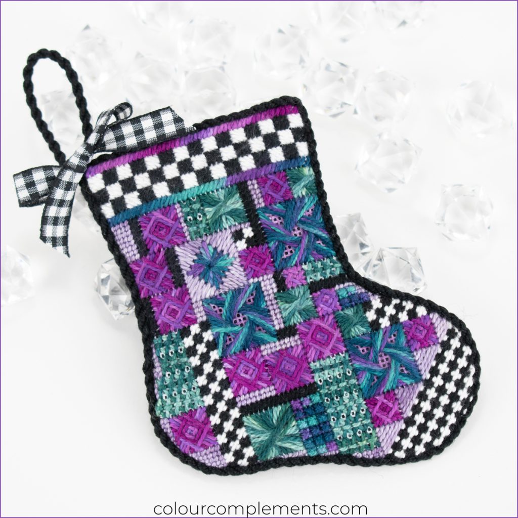 Jewel tone needlepoint Christmas stocking with black and white checkered border